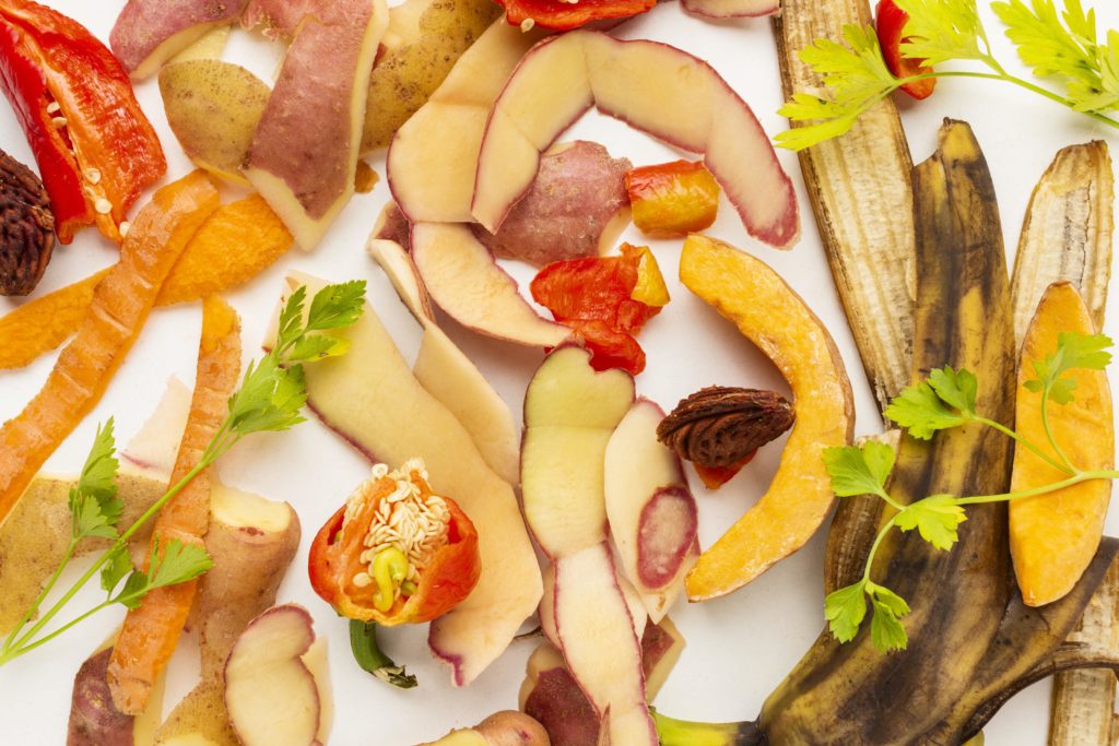 composition visuelles de biodéchets sur fond blanc : poivrons, épluchures de pomme et carotte, pomme de terre persil, peau de banane